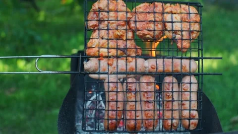 Turning grid with roasted chicken thighs. Grilling sausages meat on outdoor Stock Footage 251735200