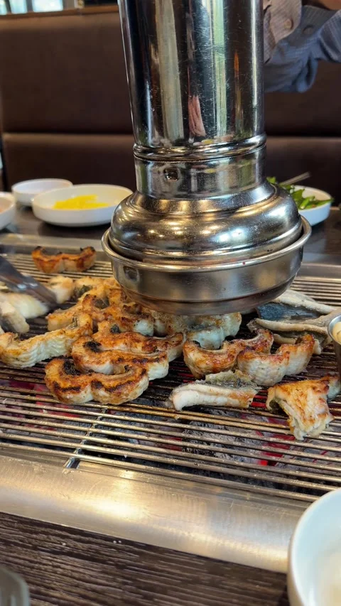 Turning Grilled Eel Slices on Charcoal Grill at Korean BBQ Stock Footage 337567013