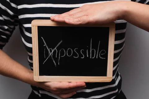 Turning the impossible into the possible. Impossible written with white chalk Stock Photos
