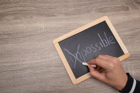 Turning the impossible into the possible. Impossible written with white chalk Stock Photos