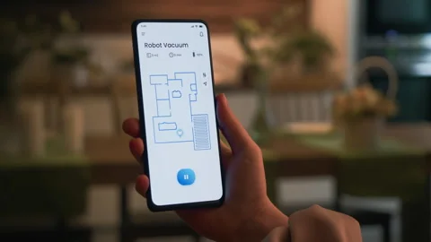 Turning on the robotic vacuum cleaner using a smartphone app. An autonomous Stock Footage 273813510
