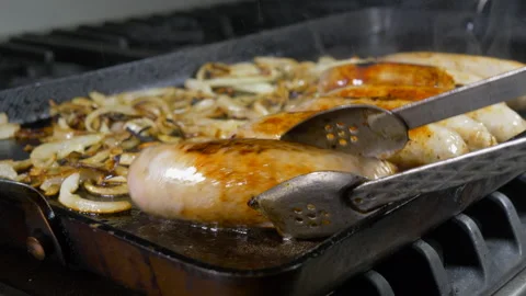 Turning six sausages in a griddle with a pair of tongs. Video stock 139211404