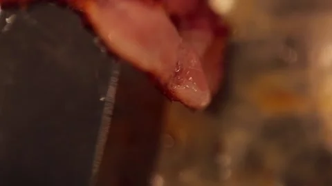 Turning sizzling bacon in slow motion with a spatula Stock Footage 149118644