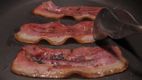 Turning slice of bacon fried on grill pan 4k Stock Footage 147571472