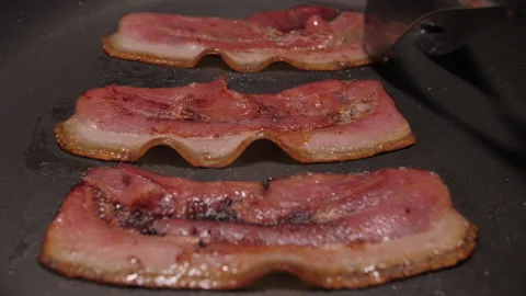 Turning slice of bacon fried on grill pan slow motion 4k Stock Footage 147576799