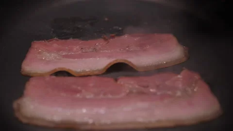 Turning slice of bacon fried on grill pan slow motion Stock Footage 147579828