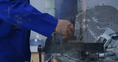 Turning tech's arm securing metal piece in vise at shop, blue jacket, perforated 库存照片
