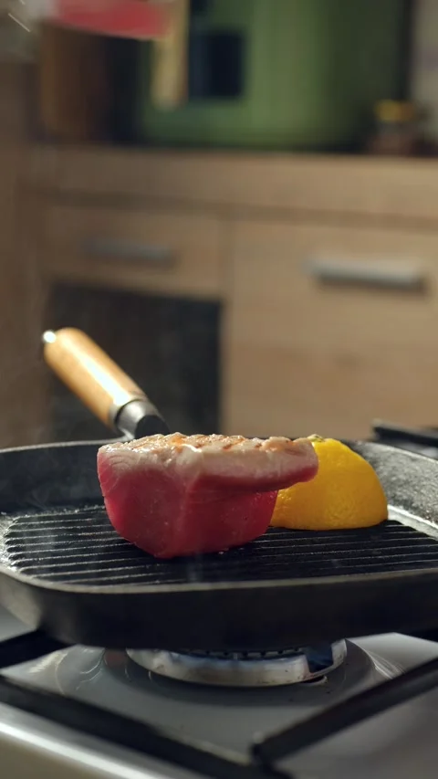 Turning tuna steak in griddle pan with kitchen tongs Stock Footage 342388866