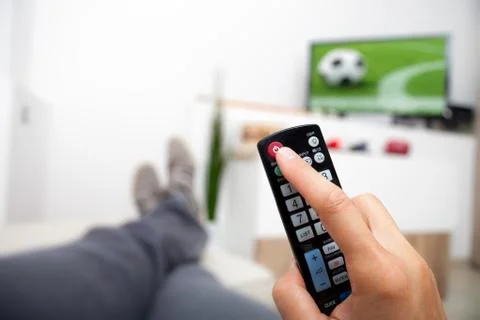 Turning off the TV. Remote control in hand. Man lying watching football and t Stock Photos