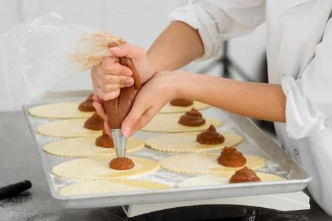 Turnovers with apple jam. Baker is squeezing yummy filling Stock Photos