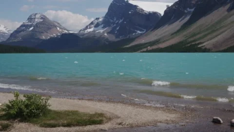 Turquoise Alpine Lake with Snow-Capped Mountains and Shoreline Waves Stock Footage 255545604