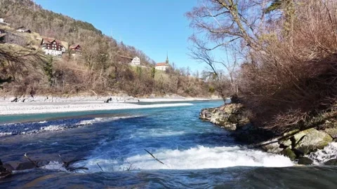 Turquoise alpine river passing under a pedestrian bridge 스톡 동영상 329506284