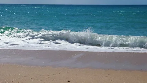 Turquoise blue ocean waves break on sandy beach slow motion Stock Footage 168974151