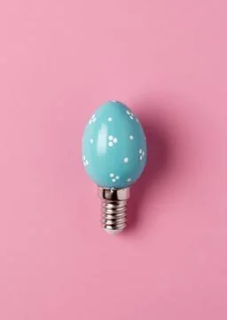 Turquoise egg shaped light bulb with white dots on pink background, playful Stock Photos