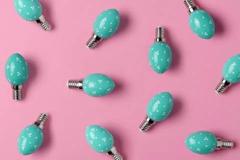Turquoise egg shaped light bulbs form playful pattern on pink background, m.. Foto stock