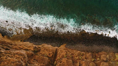 Turquoise emerald ocean waves crash on unusual volcanic rocky shore. Static top Stock Footage 220805476