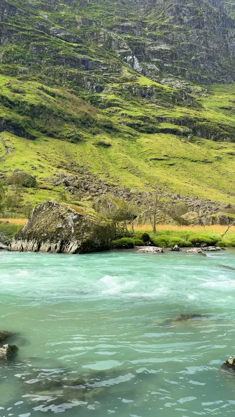 Turquoise glacial river flowing through green mountain valley Stock Footage 324598666