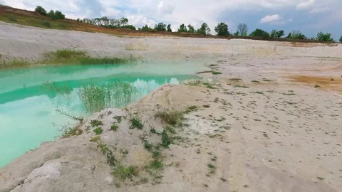 Turquoise kaolin quarry lake with white clay shores on sunny day Stock Footage 344812239