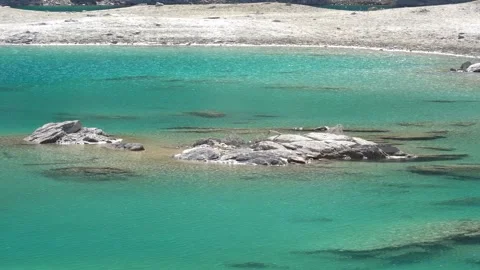 Turquoise lake water gently lapping at rocky shore Stock Footage 307482520