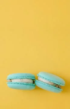 Turquoise macarons on bright yellow background, colorful french dessert min.. Stock Photos