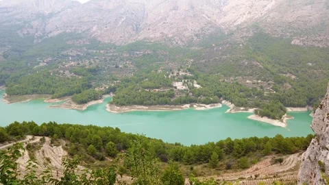 Turquoise mountain lake winding through forested valley panorama Video stock 342121808