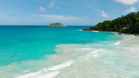 Turquoise ocean waters and a lush green peninsula meeting a sandy beach Stock Footage 301279977