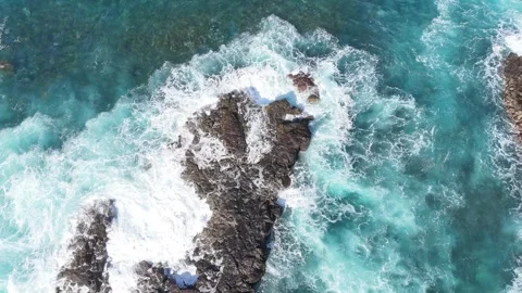 Turquoise ocean waves crash against rocky shoreline, creating foam and splashes Vídeos de archivo 341122105