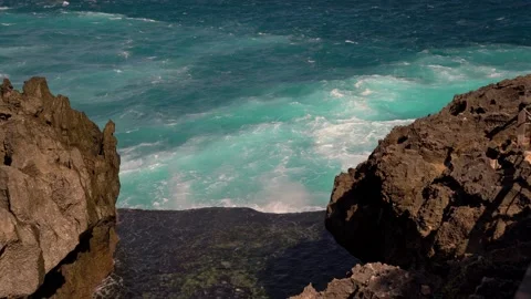 Turquoise ocean waves crashing between rugged rock formations Stock Footage 344139708
