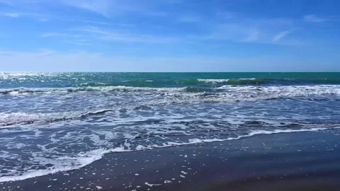 Turquoise ocean waves rolling onto beach under clear blue sky Stock Footage 310243612