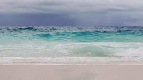 Turquoise ocean waves rolling onto sandy tropical beach under dramatic sky Stock Footage 320935509