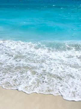 Turquoise Ocean Waves Rolling onto Sandy Beach Stock Photos