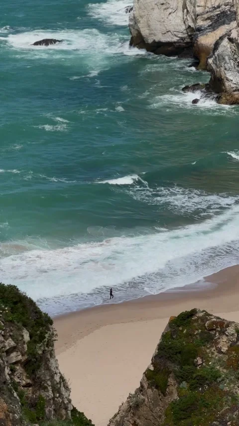 Turquoise ocean waves on sandy cove below sea stacks, Portugal coast Stock Footage 346582485