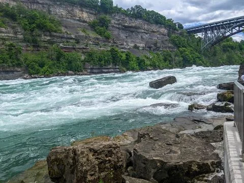 Turquoise rapids flow on the Niagara River with layered limestone Stock Photos