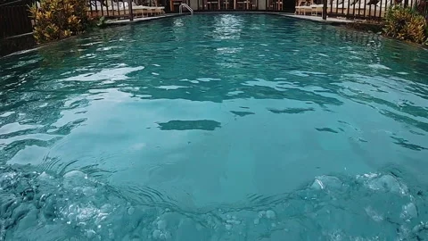 Turquoise resort pool viewed from water level with bare feet and splashing Stock Footage 338441076