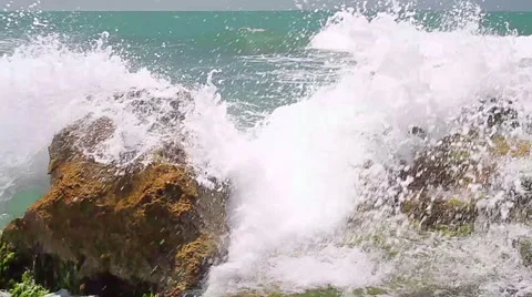 Turquoise rolling wave slamming on the rocks . Stock Footage 49625773