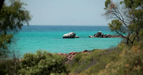 A turquoise sea with rocks viewed through foliage, Dunsborough Western Australia Stock Footage 269585034