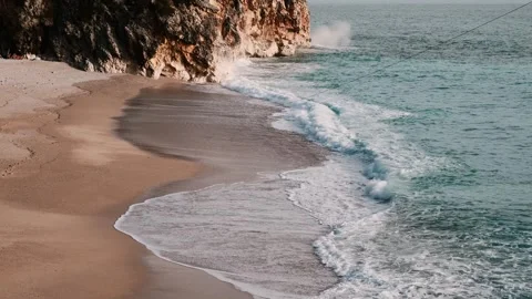 Turquoise sea waves gently rolling onto golden sandy beach Stock Footage 328932969