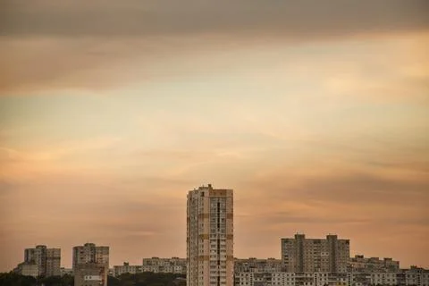 Turquoise sky between clouds over the houses of a modern city at sunset Stock Photos