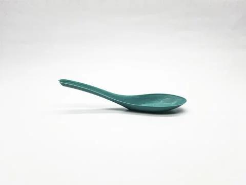 Turquoise spoon resting on a white surface in a simple studio setting Stock Photos