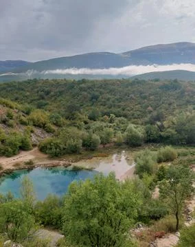 Turquoise spring surrounded by forest and mountains. Stock Photos