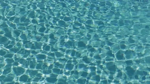 Turquoise surface of sunlit swimming pool.  Light ripples reflection refraction Stock Footage 185553070