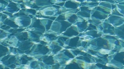 Turquoise surface of sunlit swimming pool.  Light ripples reflection refraction Stock Footage 185553264