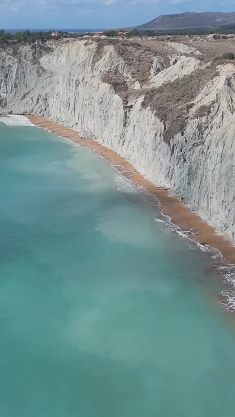 Turquoise water lapping sandy beach below white cliffs Stock Footage 290450429