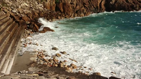 The turquoise water of the ocean, the waves break on the stone shore in sunny Stock Footage 240850294