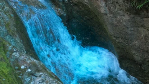 Turquoise waterfall cascading down rocky mountainside Stock Footage 312469533
