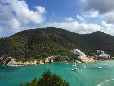 Turquoise waters  and pine covered hills of Cala Llonga bay, Mediterranean se Stock Photos