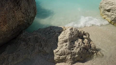 Turquoise Wave Washing Around Big Coastal Boulders on Sand Stock Footage 346270348