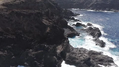 Turquoise waves breaking against dark volcanic cliffs of La Palma, generating Stock Footage 308404723
