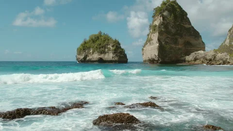 Turquoise waves gently rolling over the shallow waters as rocks and cliffs form Video stock 289481757