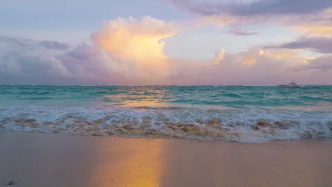 Turquoise waves lap gently on a sandy beach with a colourful sky Stock Footage 316244617